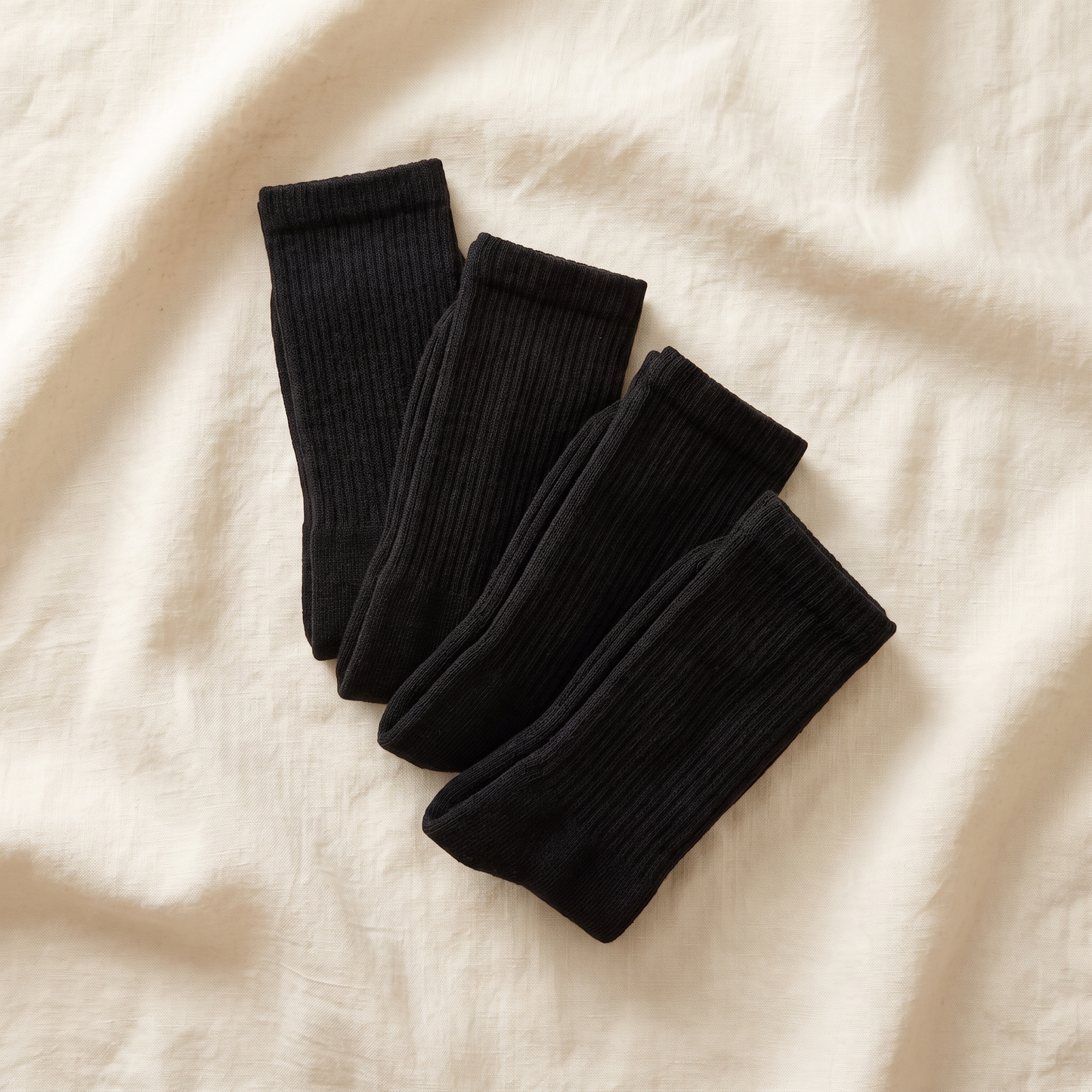 Work Bundle flat lay - 4 pairs of black alpaca work socks folded on cream linen