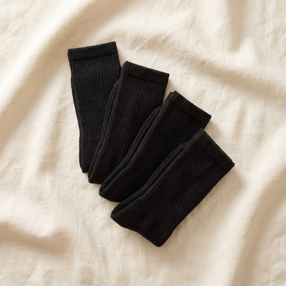 Work Bundle flat lay - 4 pairs of black alpaca work socks folded on cream linen