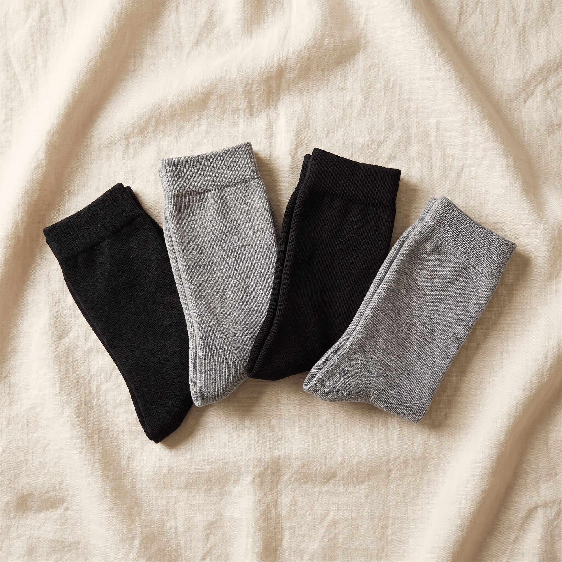 Crew Bundle flat lay - 4 pairs of alpaca crew socks folded on cream linen